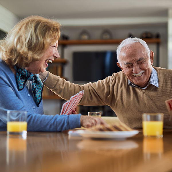 An older couple joyfully laughing together at a table, enjoying each other's company.