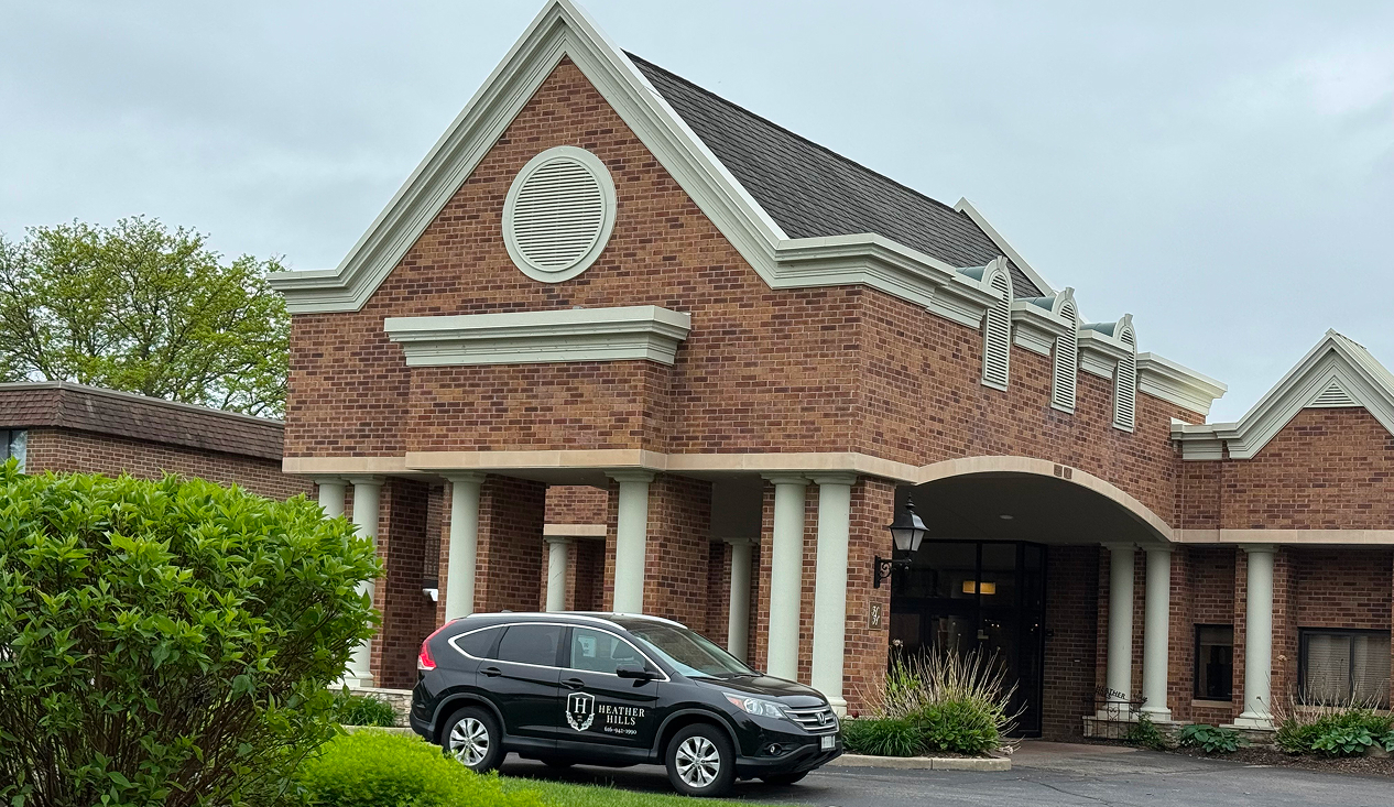 A parked car in front of a brick building, showcasing the structure's texture and color.