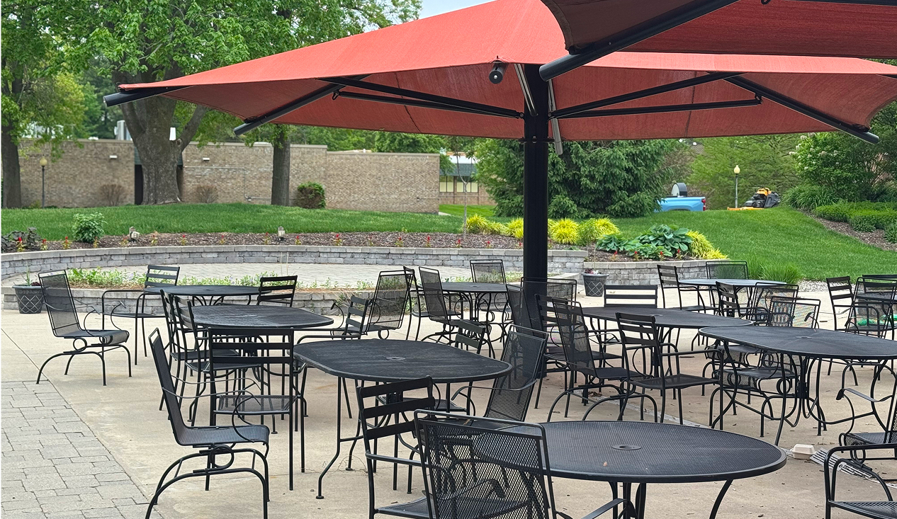 patio featuring tables and chairs shaded by a large umbrella, perfect for outdoor dining.